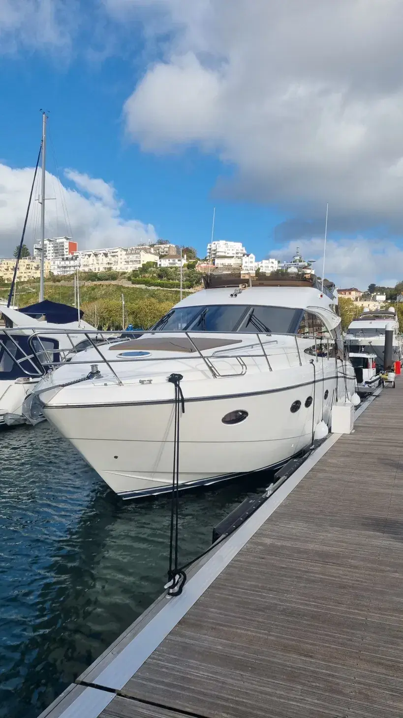 A detailed motor yacht berthed in Torquay marina under blue sky